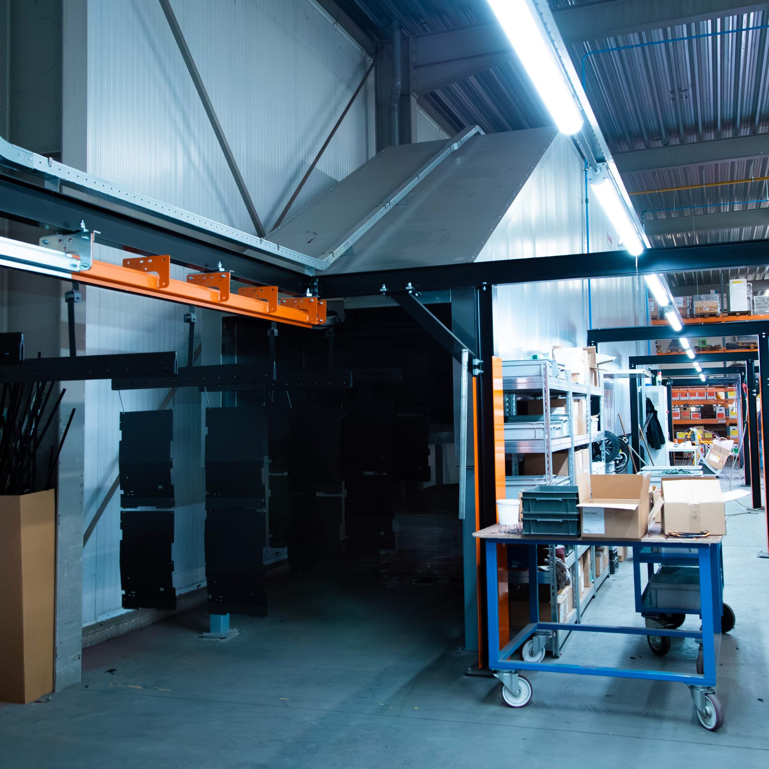 Coatinglijn met hangende plaatwerk onderdelen in poedercoatstraat binnen metaalbewerking productiehal