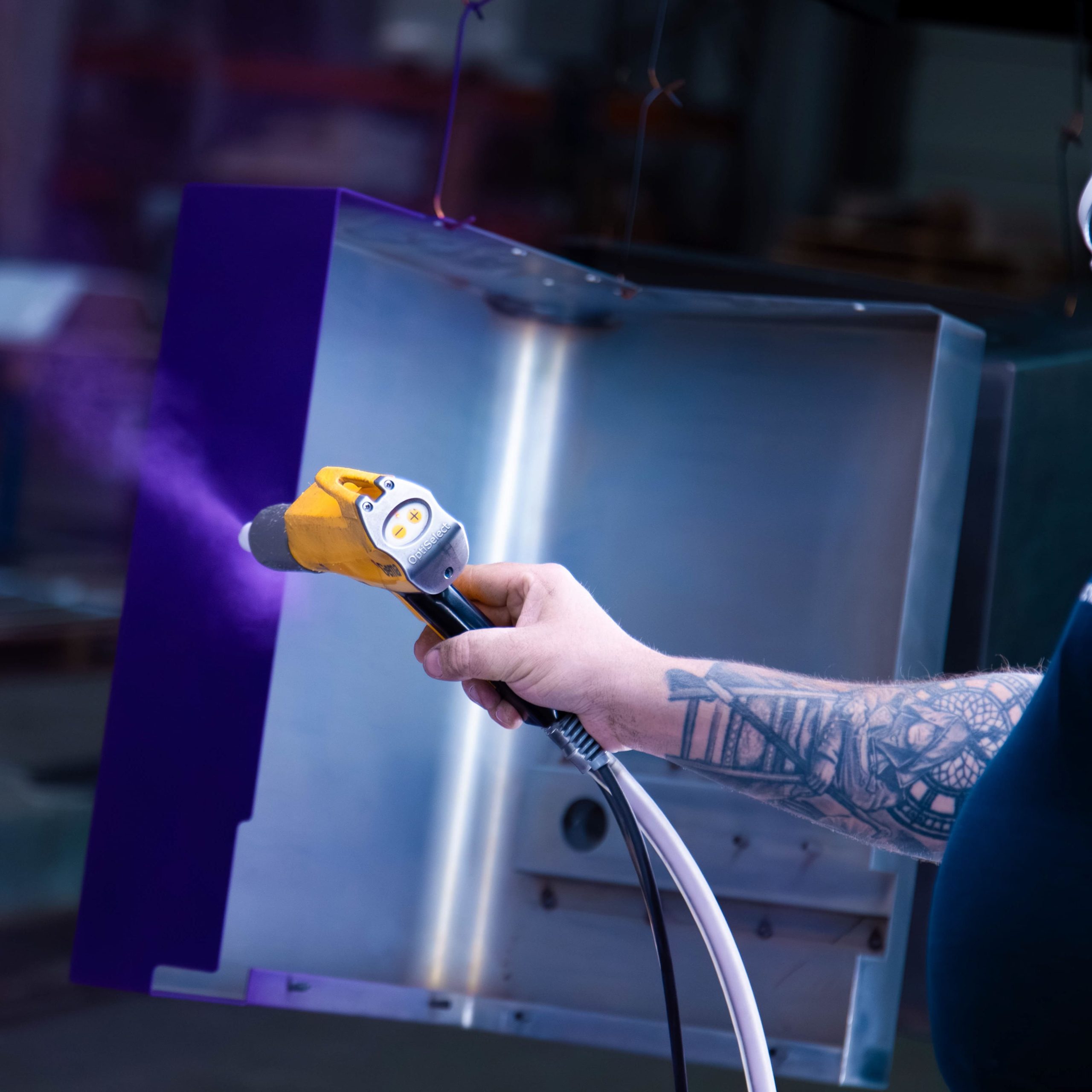 Poedercoaten van metalen behuizing met elektrostatisch spuitpistool in productieomgeving